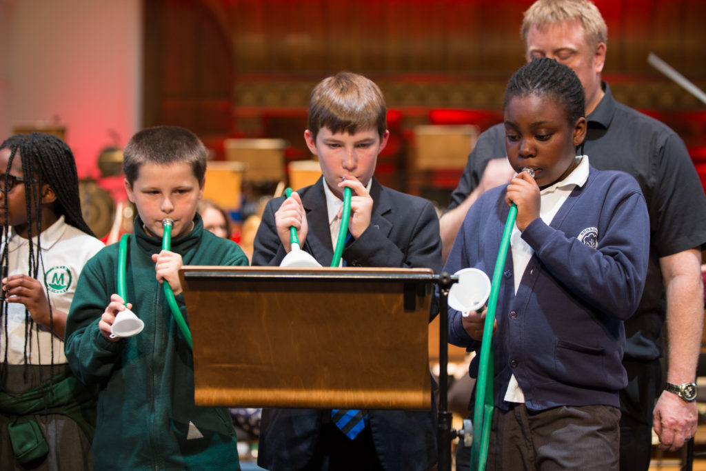 Three student participants of LCO's Music Junction programme playing toy horns in the Toy Symphony.