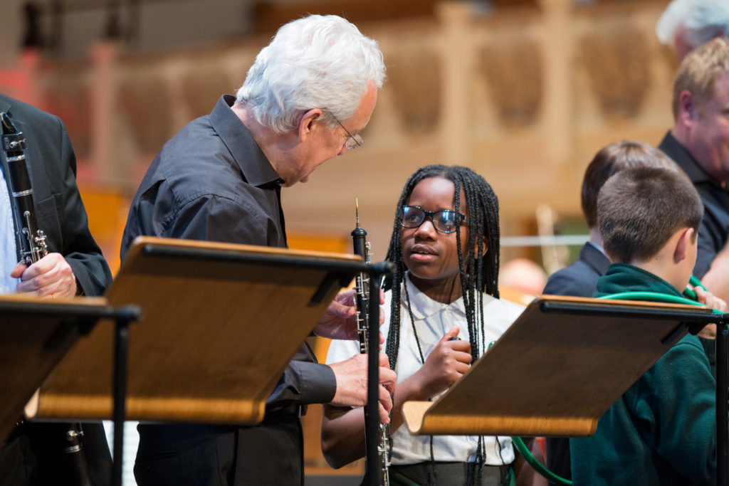A young student participant of the LCO's Music Junction programme talks to one of the orchestra's oboists.